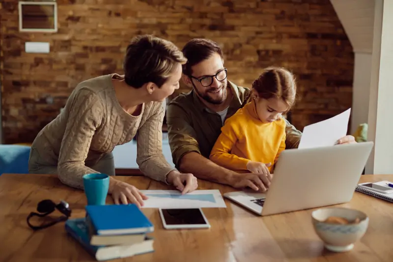 Happy working father using his laptop with his family at home